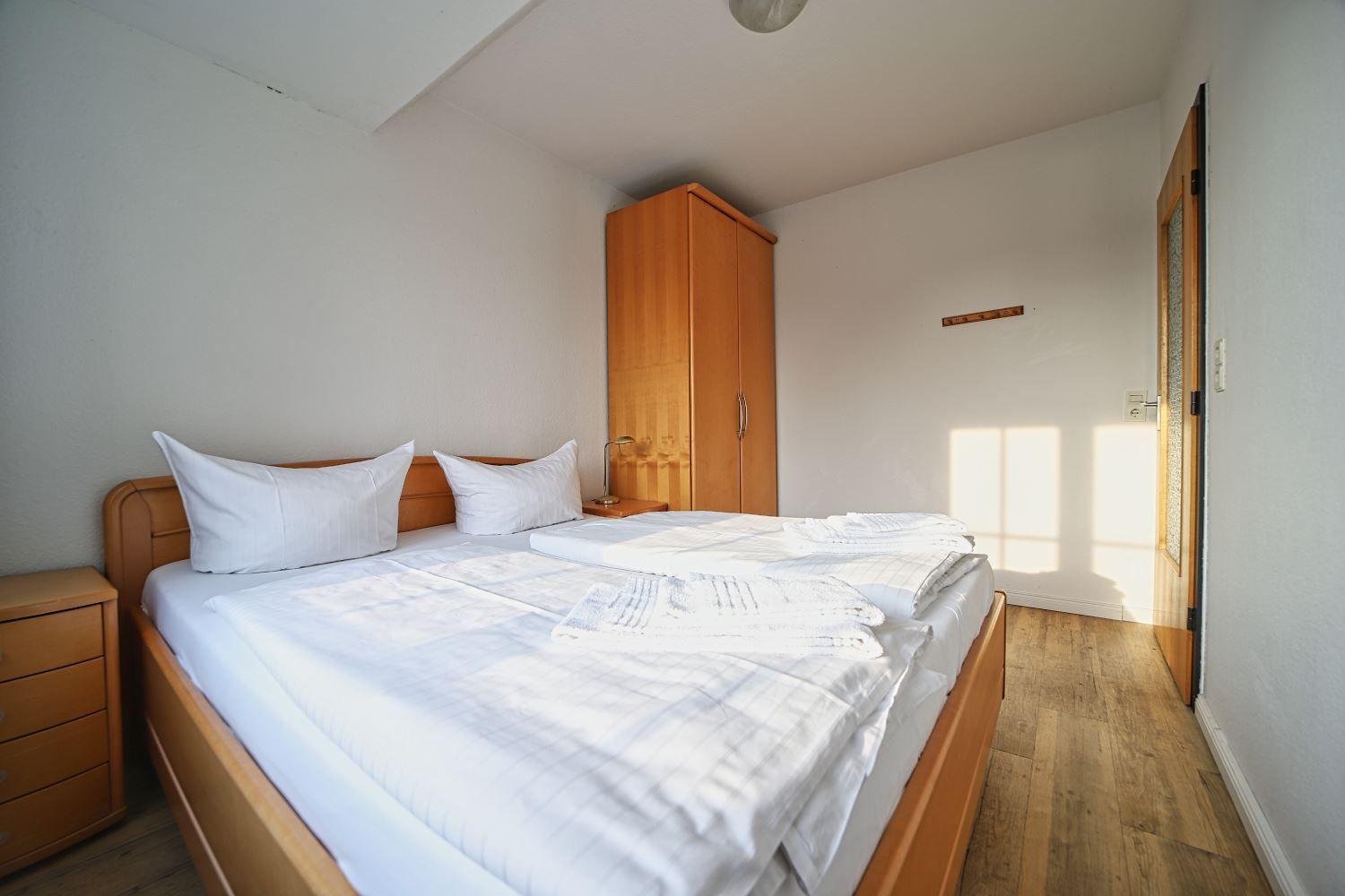 Schlafzimmer mit Doppelbett, Kleiderschrank und Holzboden.