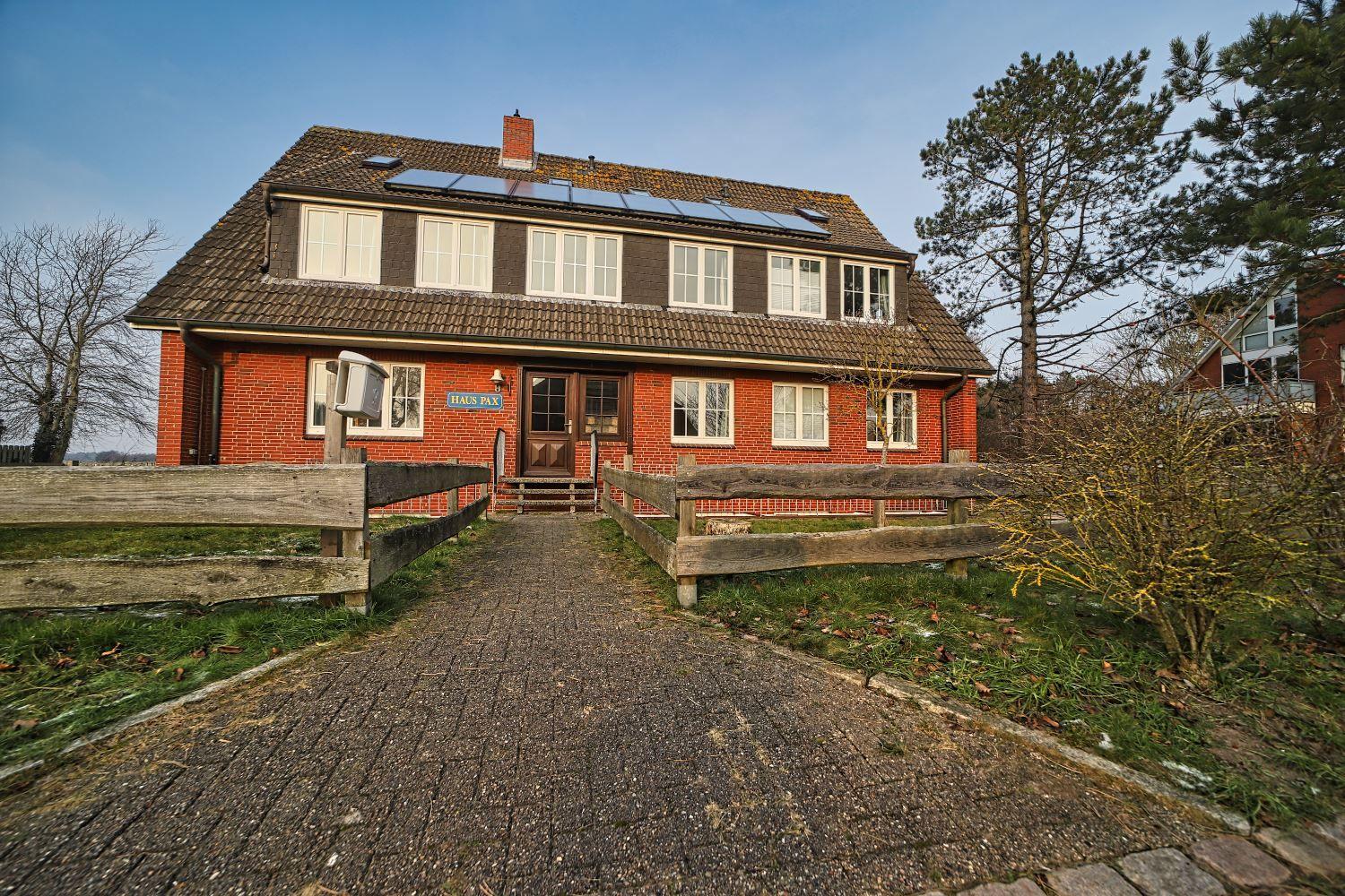 Rotes Backsteingebäude mit Solaranlage und Holzstegen zur Eingangstür.