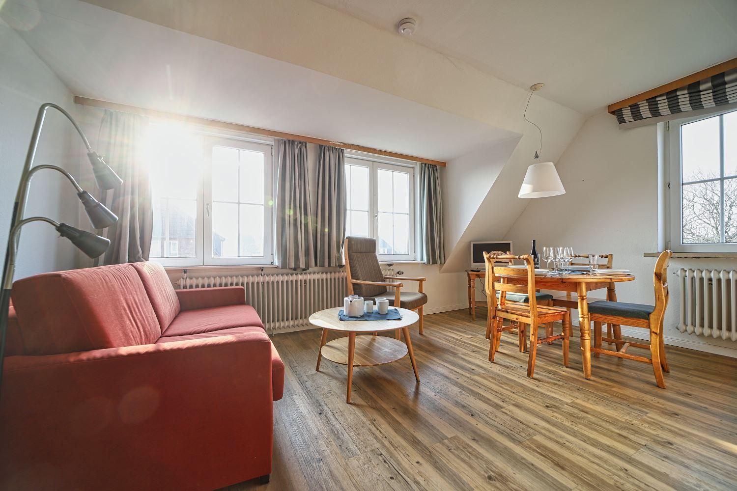 Wohn- und Essbereich mit Holzboden, Sofa, Tisch und Stühle.