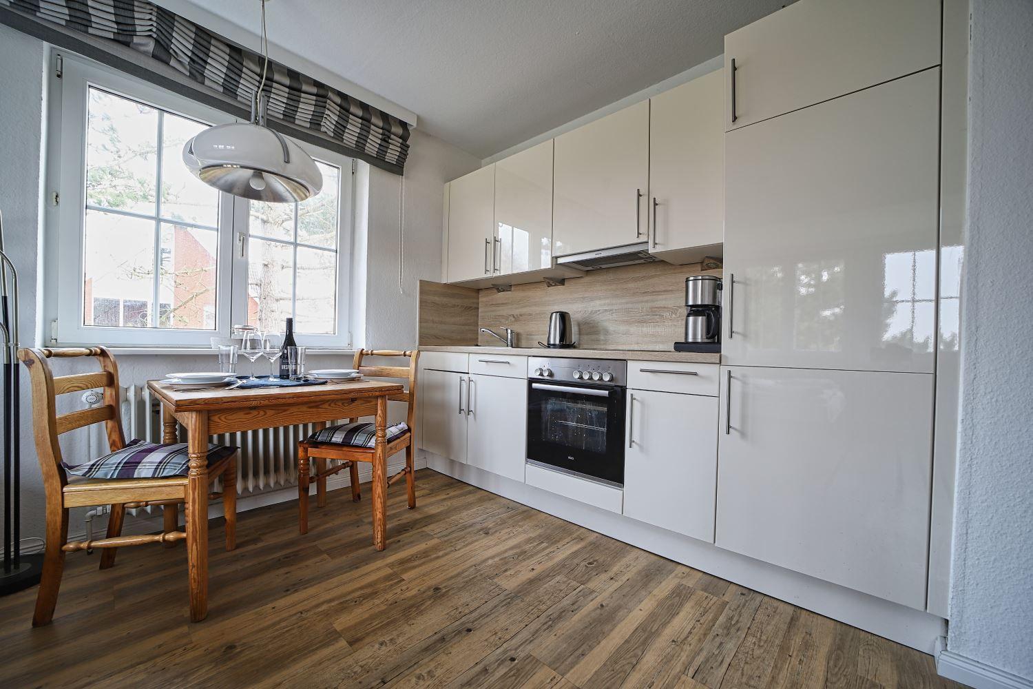 Küche mit Essbereich, Holzboden und Fenster mit Blick nach draußen.