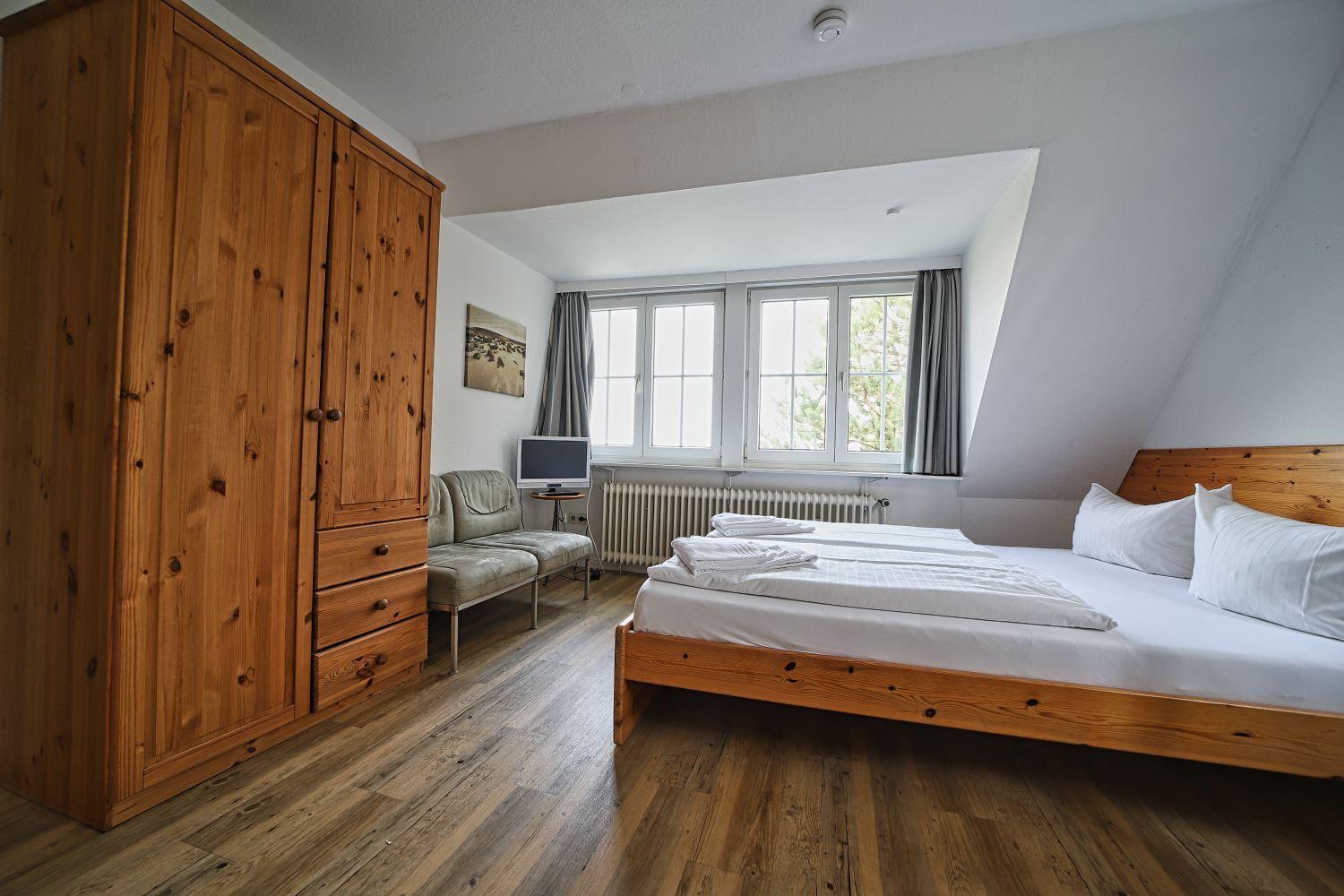 Schlafzimmer mit Doppelbett, Holzmöbel und Fenster mit Blick.