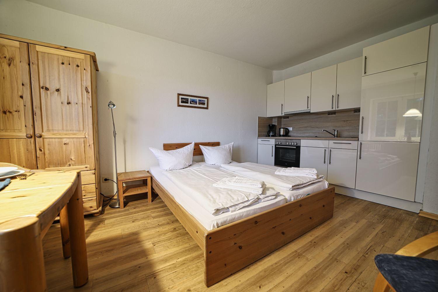 Ein Schlafzimmer mit Doppelbett, Küchenzeile und Holzmöbeln.