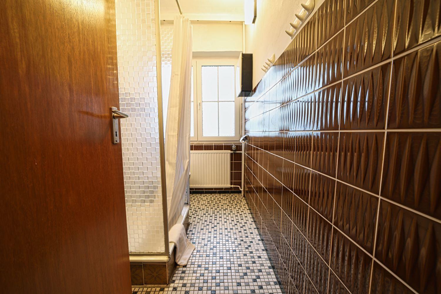 Badezimmer mit braunen Fliesen, Mosaikboden und Fenster