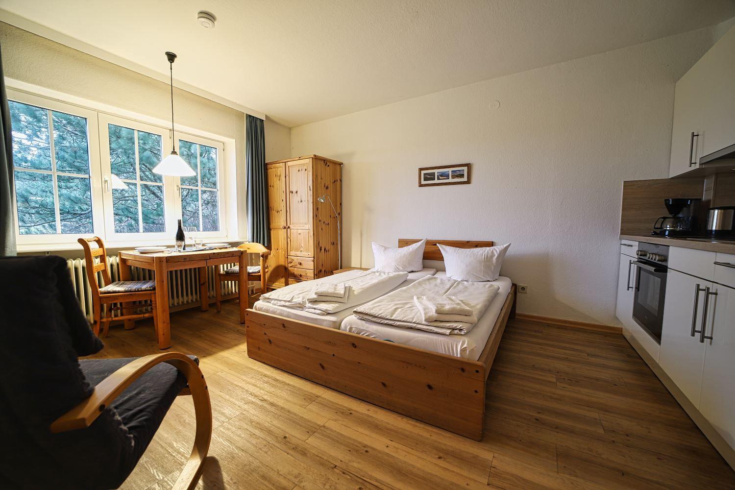 Schlafzimmer mit Bett, Tisch, Stühlen und Küchenzeile.