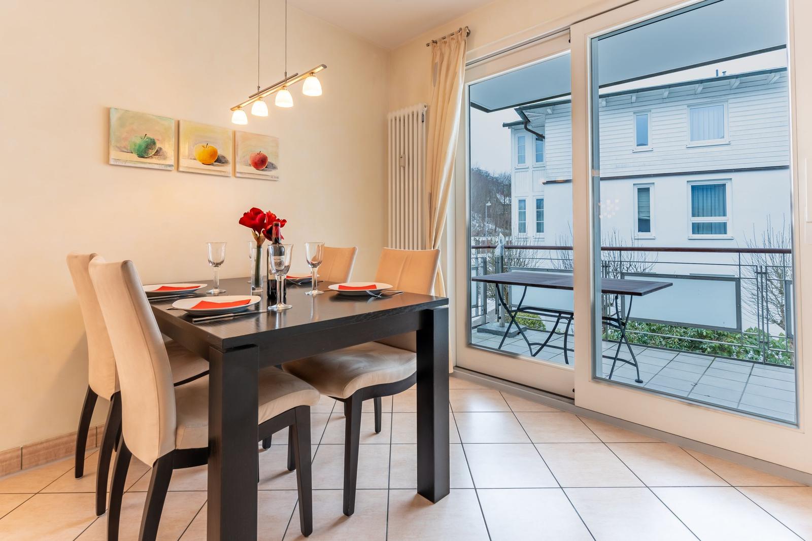 Esszimmer mit Tisch, Stühlen und Balkonansicht.