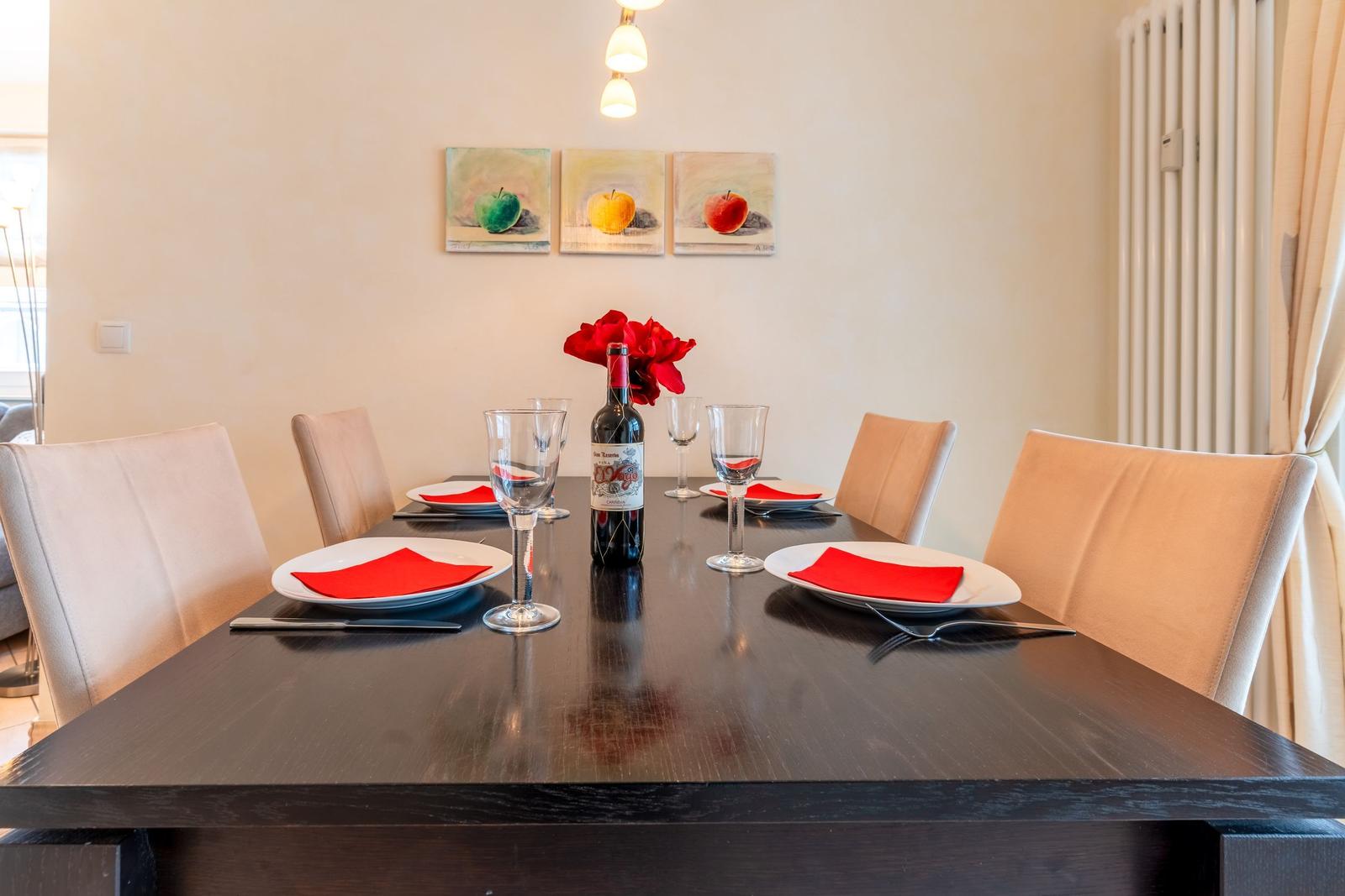 Esstisch mit sechs Stühlen, roten Servietten und einer Weinflasche.