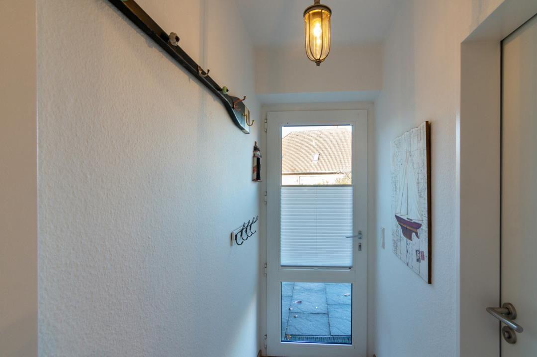 Flur mit Wandgarderobe, Fenster und Wandbild mit Segelboot.