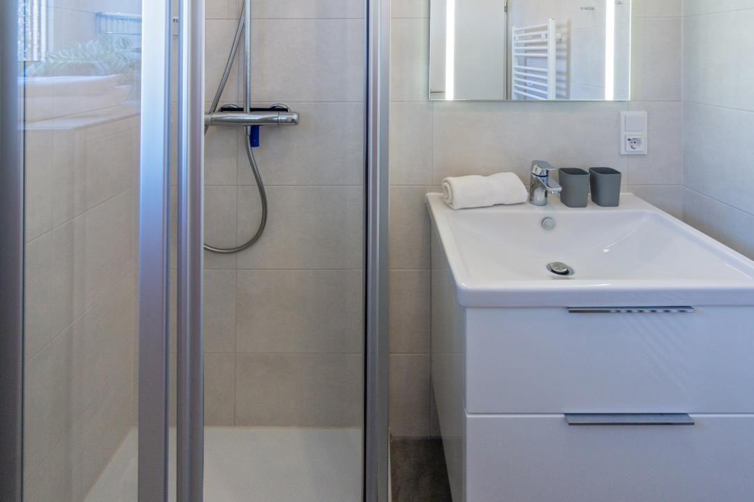 Dusche mit Glaswand, Waschbecken und Spiegel