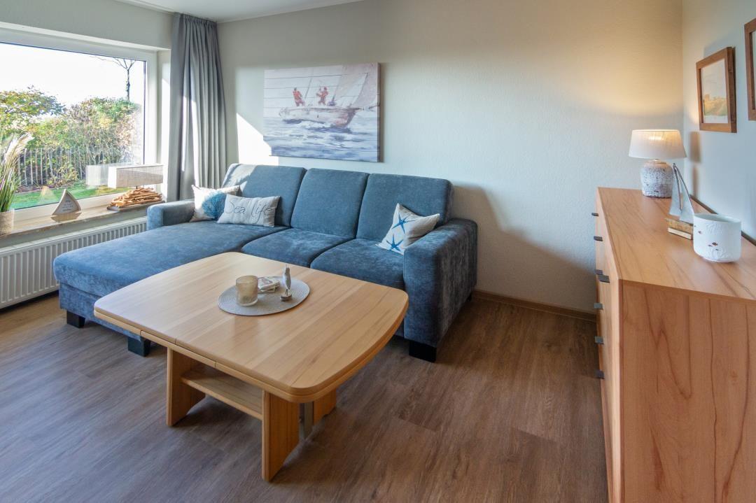 Wohnzimmer mit Sofa, Tisch und Fensterblick auf Garten