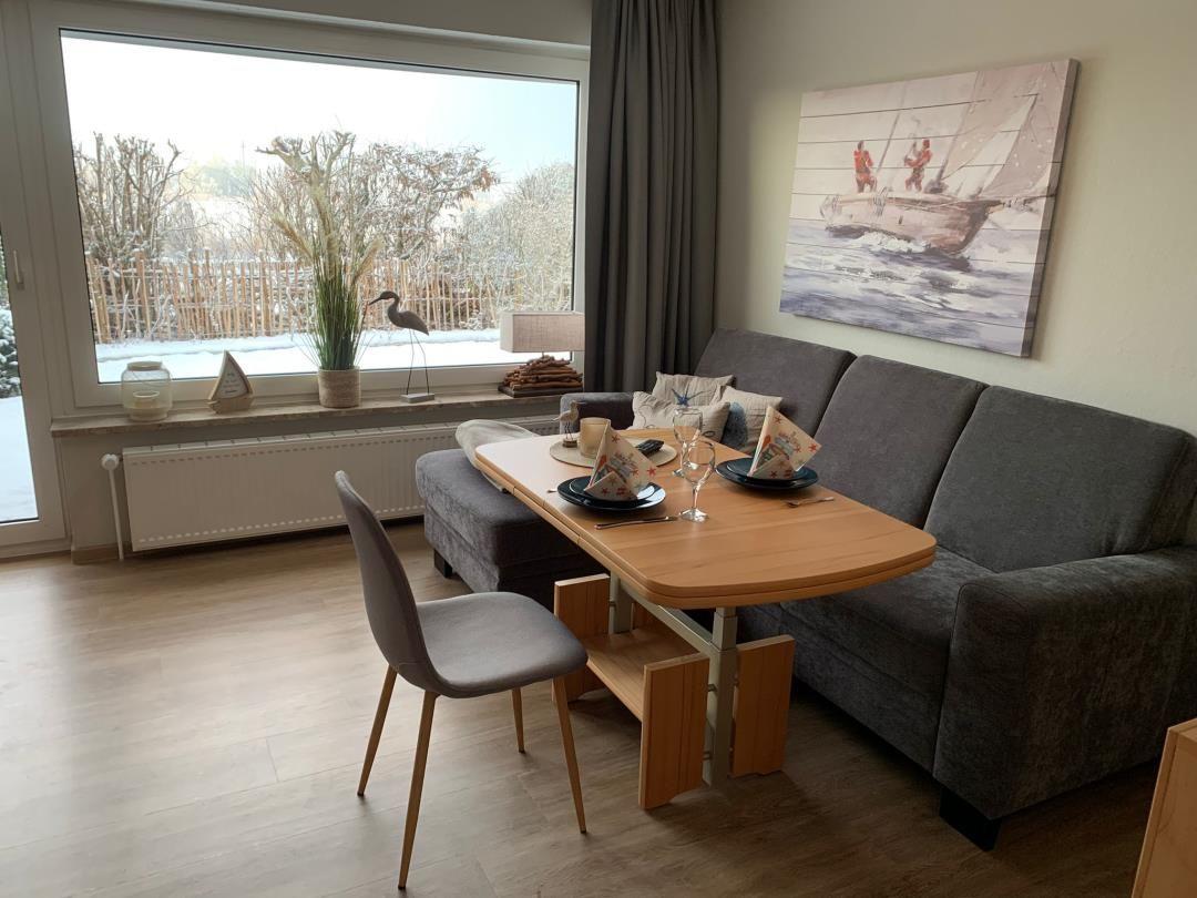 Essbereich mit Tisch, Stuhl und Sofa. Große Fensterfront mit Blick auf Garten.