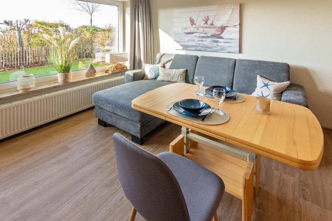 Essbereich mit Esstisch und Sofa. Fenster mit Blick auf Garten.
