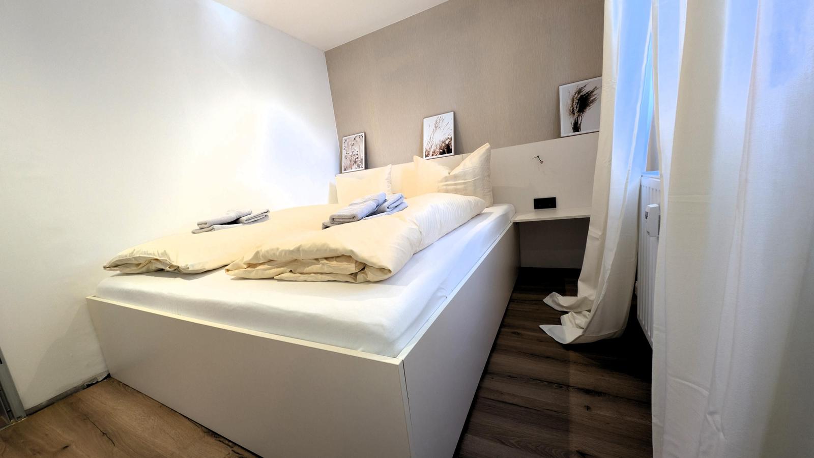 Schlafzimmer mit Bett, Nachttisch und Bildern an der Wand.