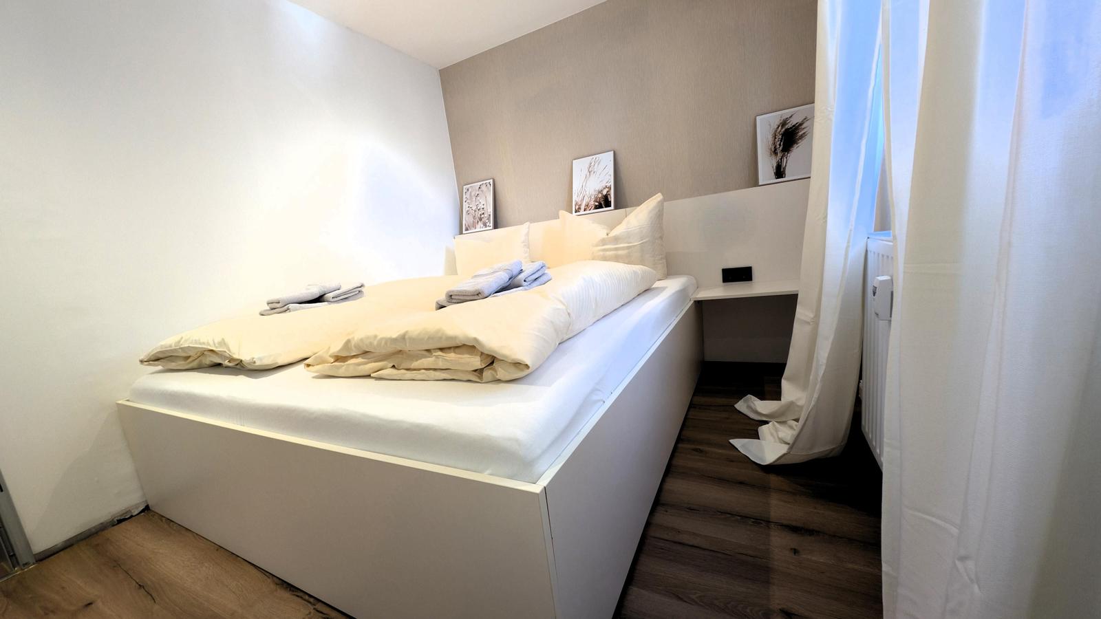 Schlafzimmer mit Bett, Nachttisch und Bildern an der Wand.