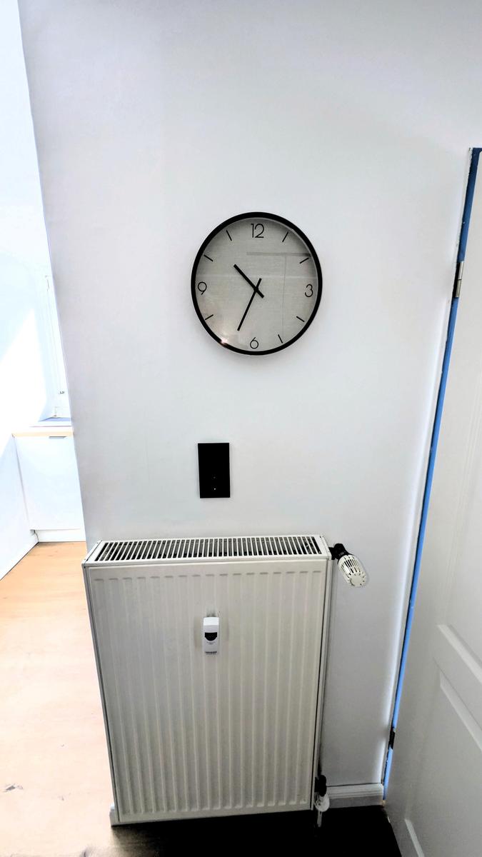 Wanduhr über Heizkörper an weißer Wand in Flur