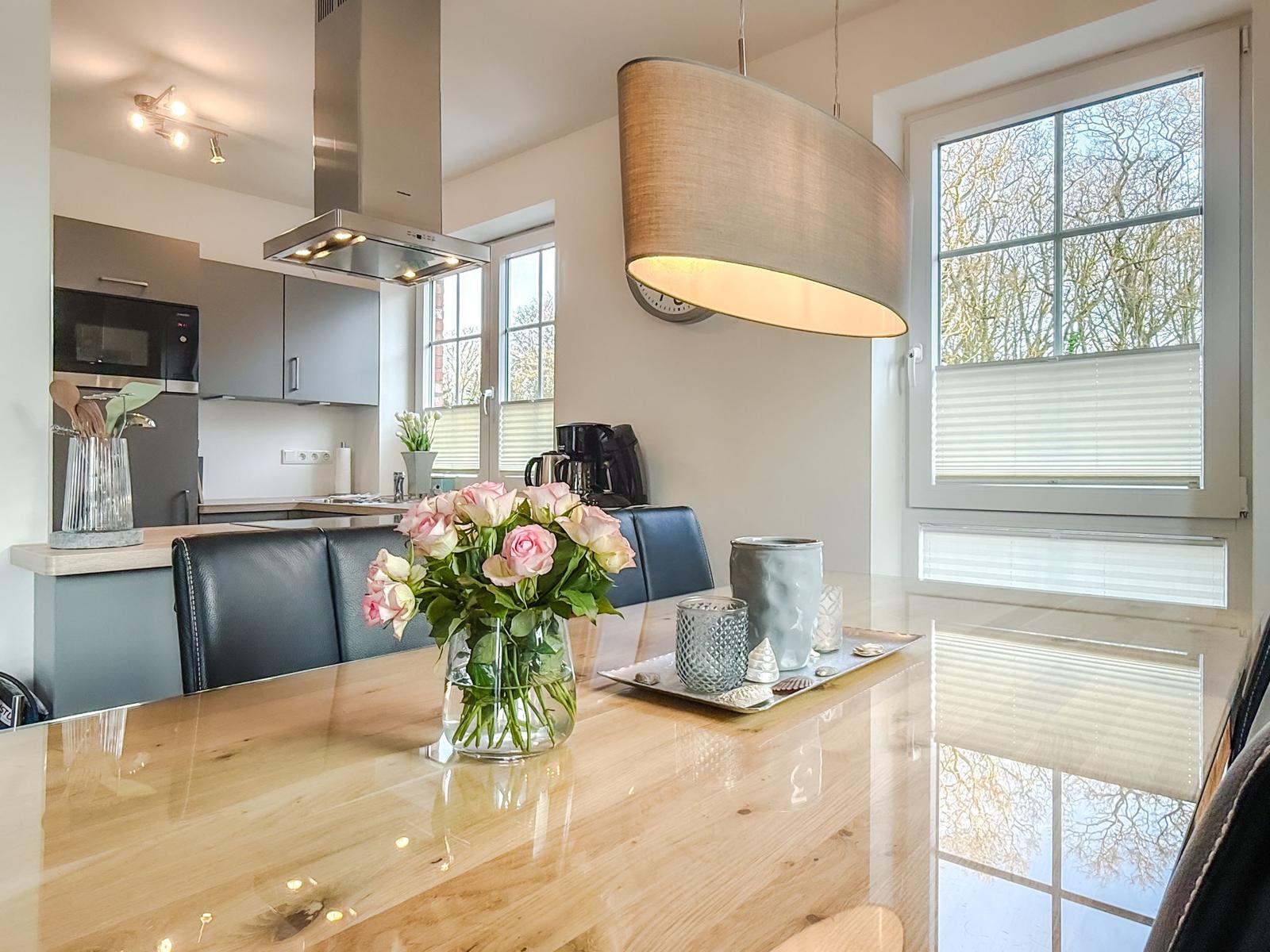 Essbereich mit Holztisch, Blumen und Sicht auf Bäume durch Fenster