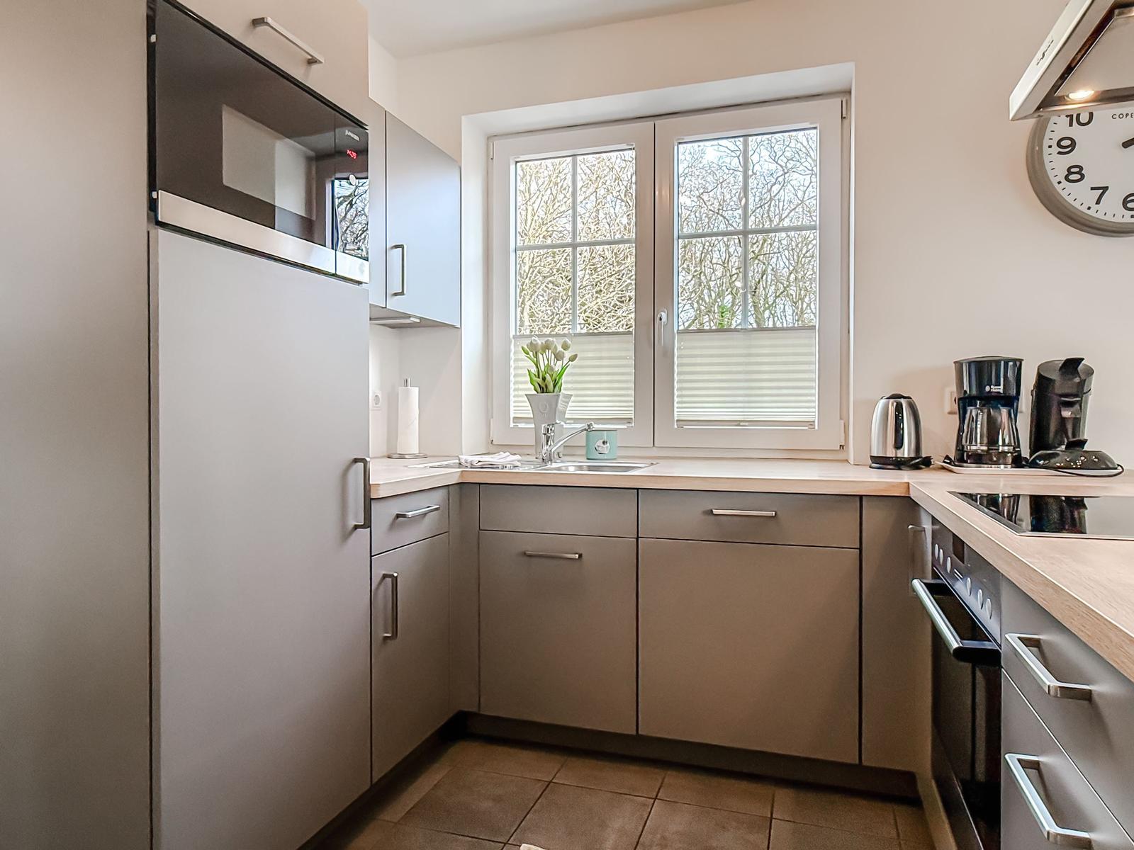 Küche mit Fenster, Spüle, Kühlschrank und Kochgeräten.