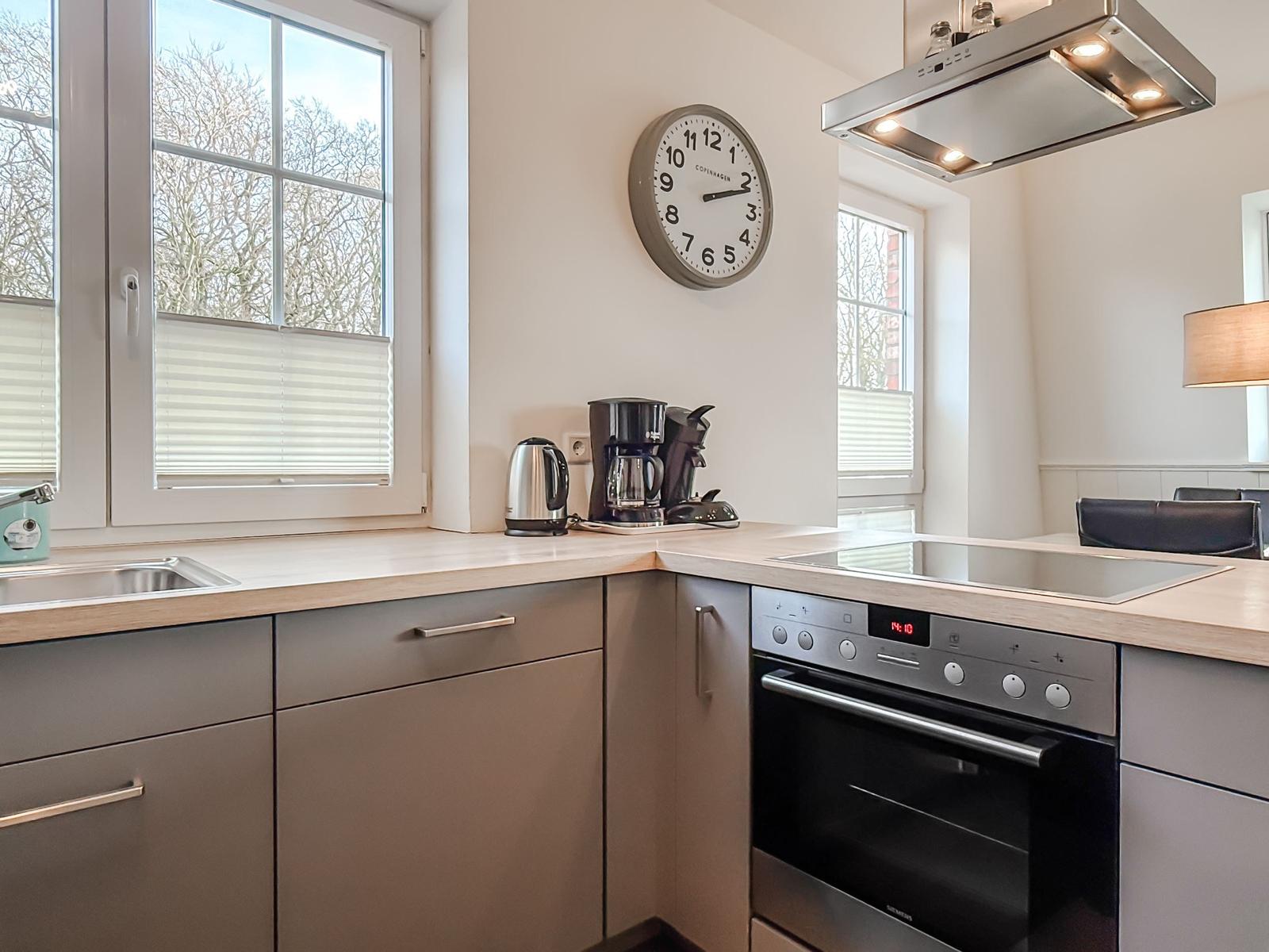 Küche mit Edelstahlgeräten, Holzoberfläche und Fenster zur Aussicht.