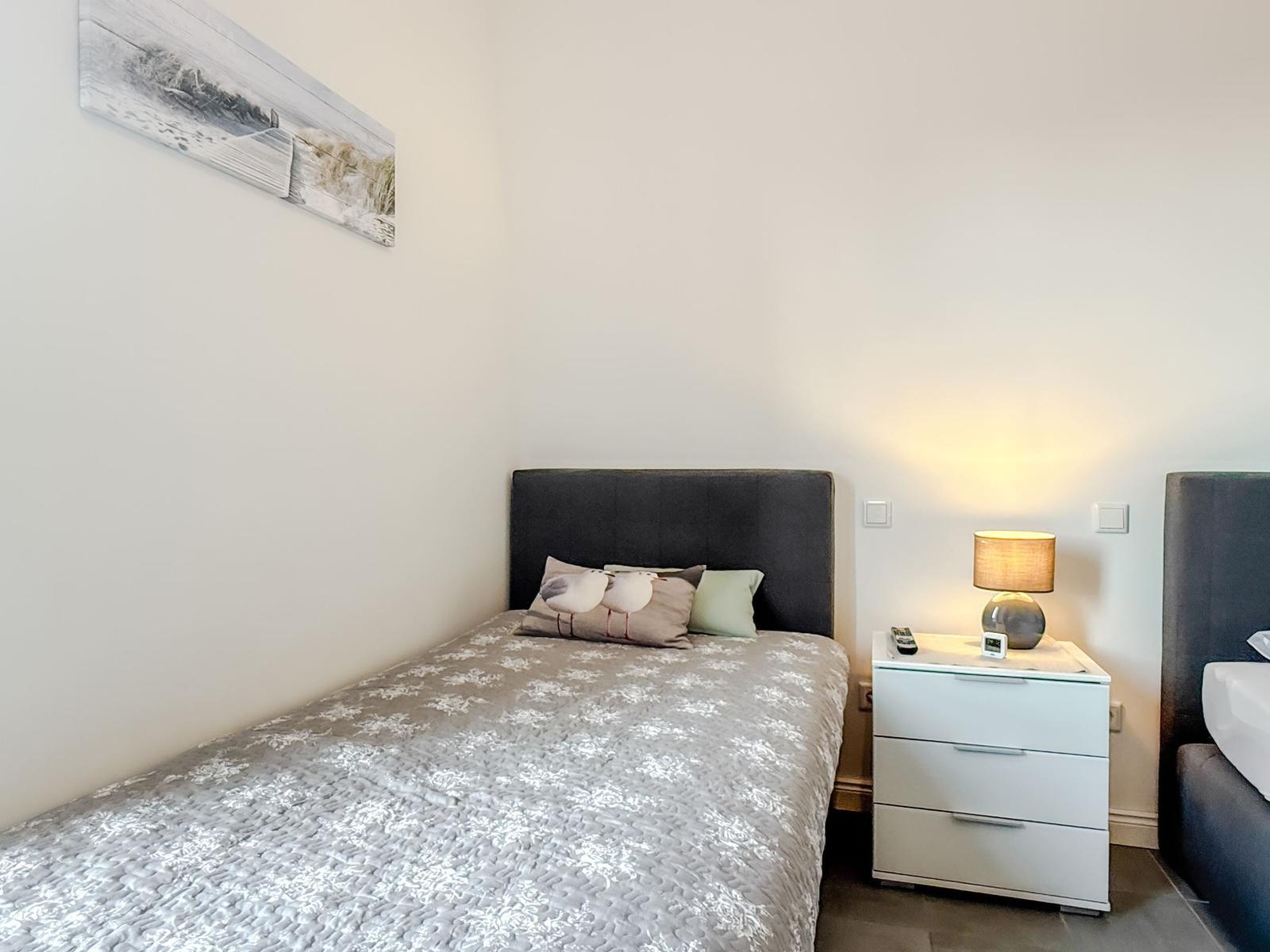 Schlafzimmer mit Bett, Nachttisch und Wandbild.