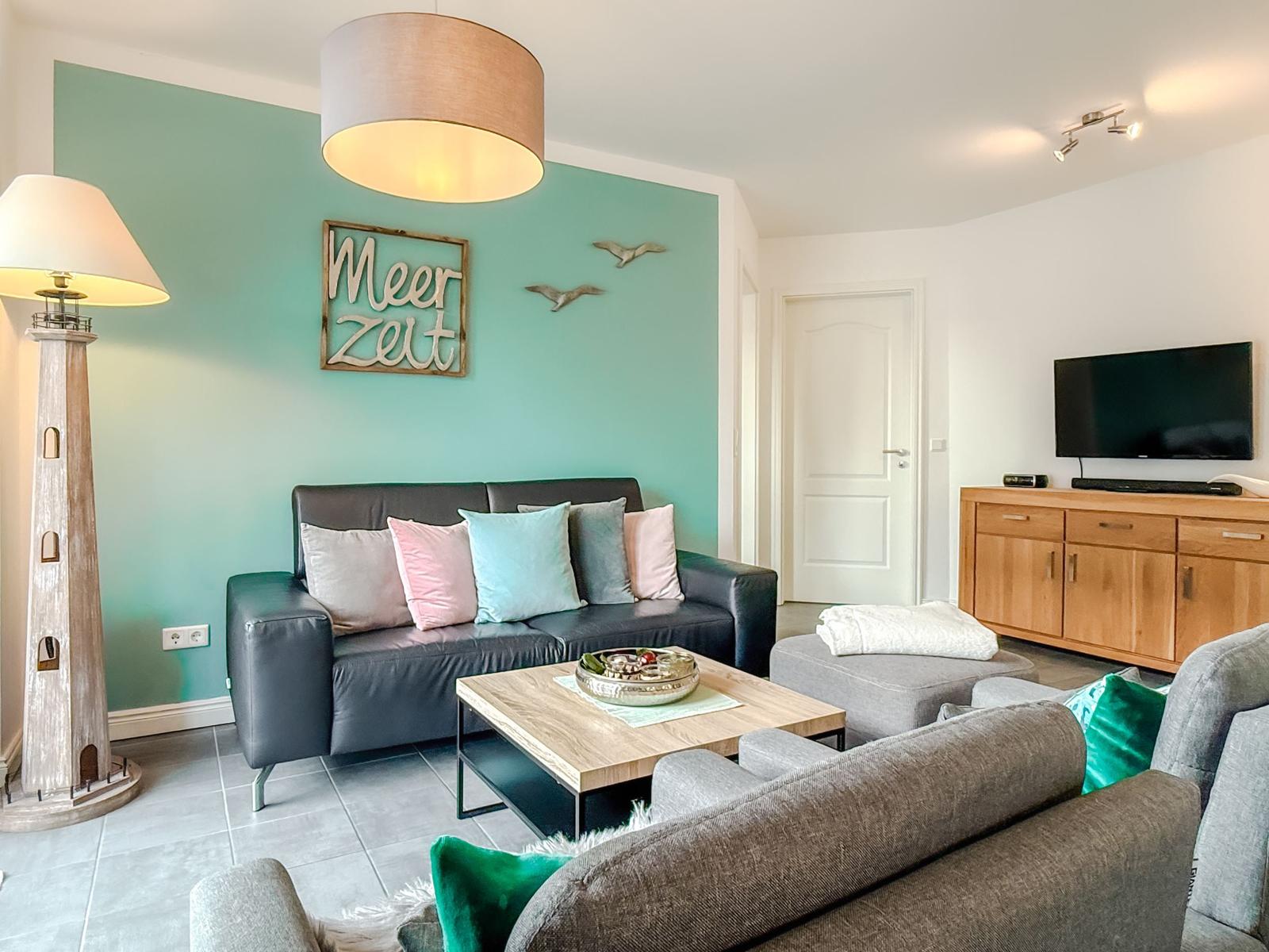 Wohnzimmer mit Sofa, Couchtisch und Fernseher an Wand.