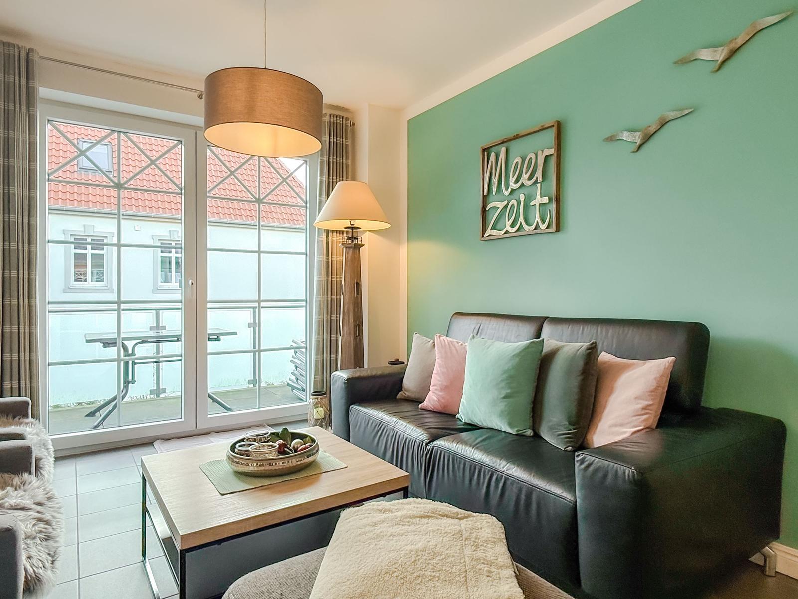 Ein Wohnzimmer mit Sofa, Couchtisch und Blick auf Balkon.