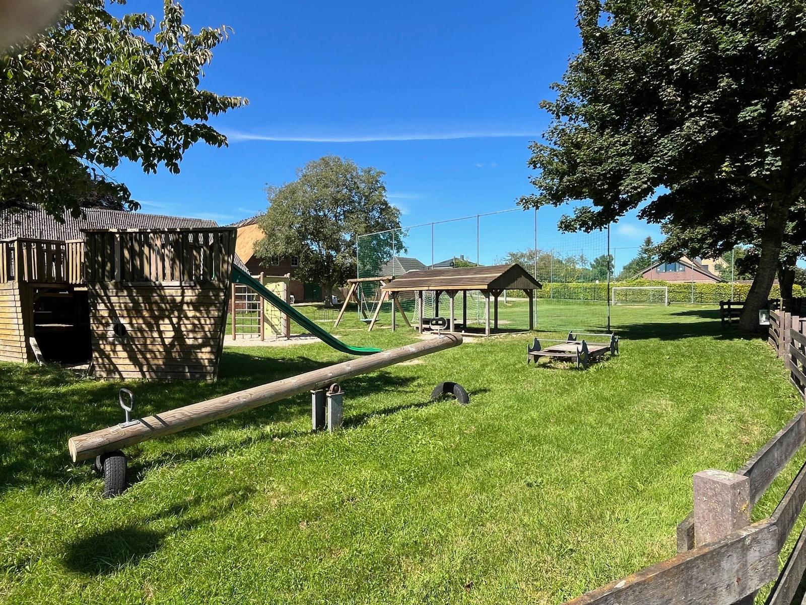 Large garden with wooden playground, slide, and swing.