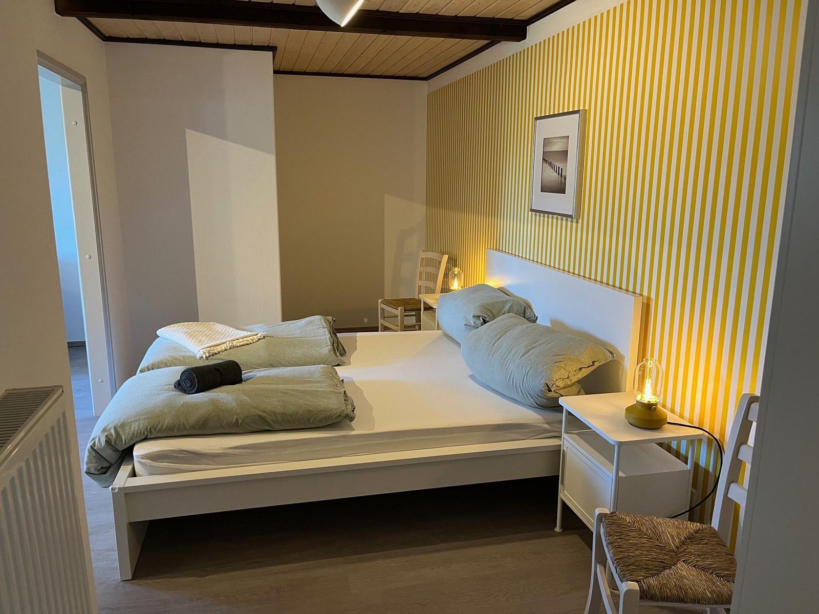 Bedroom with bed, nightstand, and yellow-white striped wall