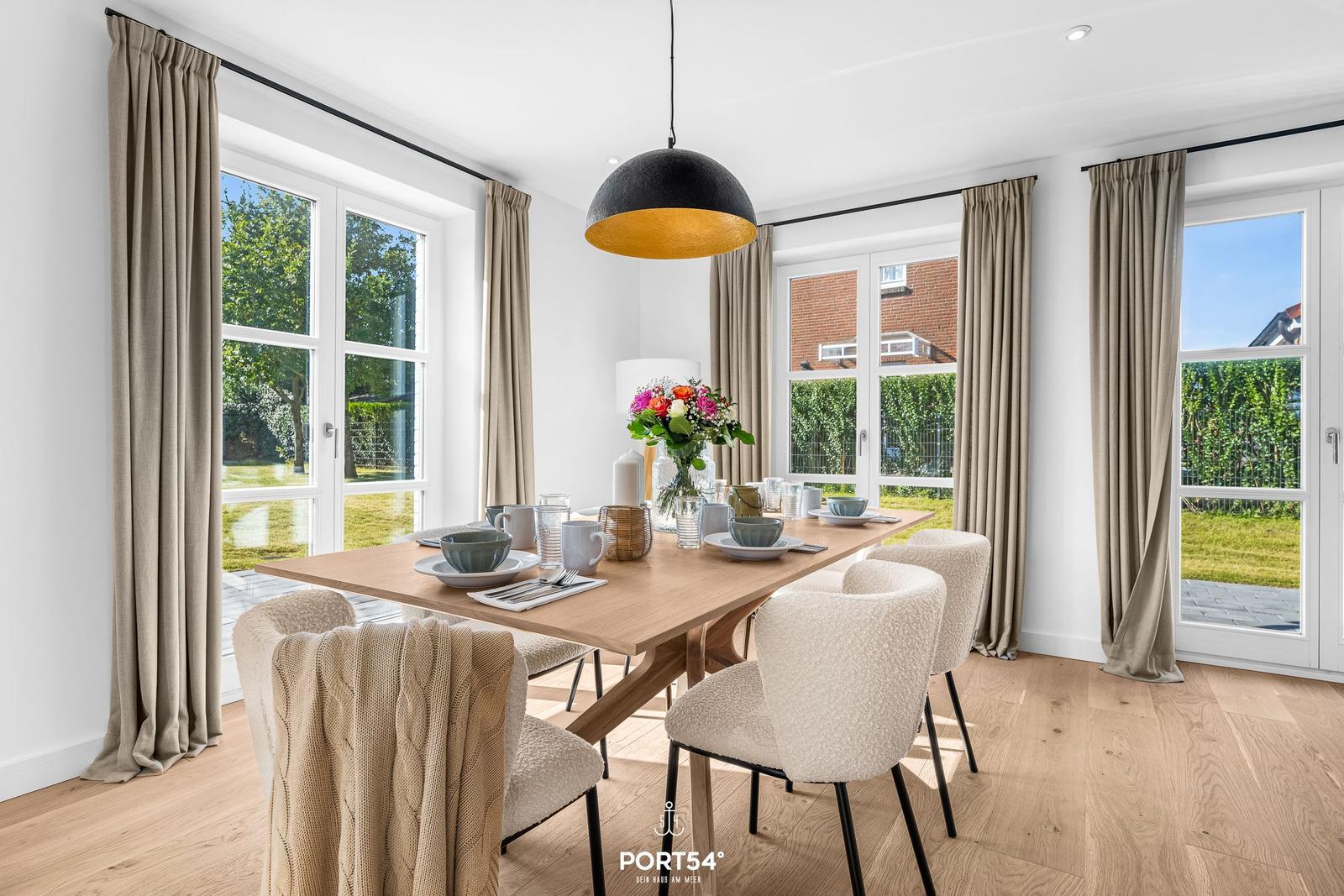 Esszimmer mit Holztisch, Stühlen und Blick auf Garten.