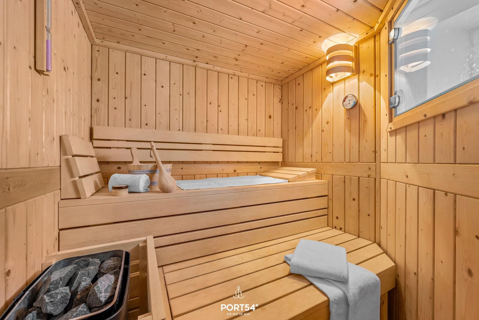 Holzsauna mit Sitzbänken, Steinen und Handtuch