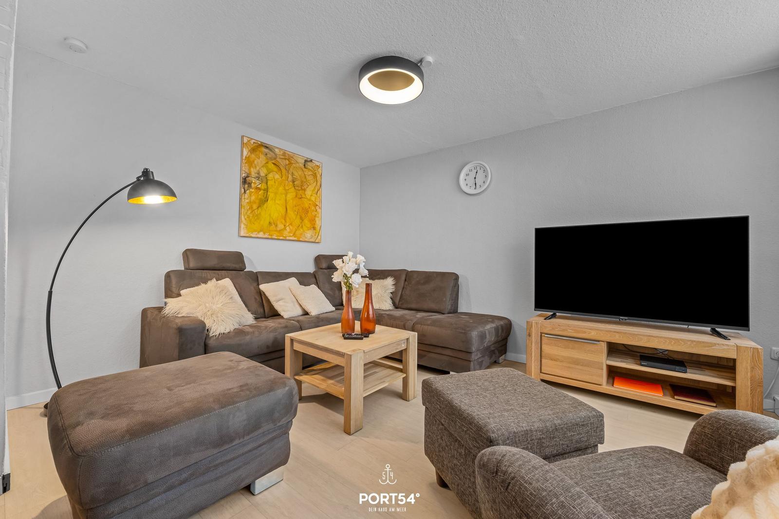 Wohnzimmer mit Sofa, Couchtisch und Fernseher auf Holzkonsole.