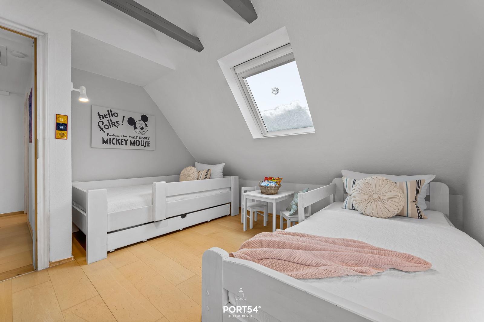 Zimmer mit zwei Betten, Dachschräge und Dachfenster. Wandbild mit Mickey Mouse.