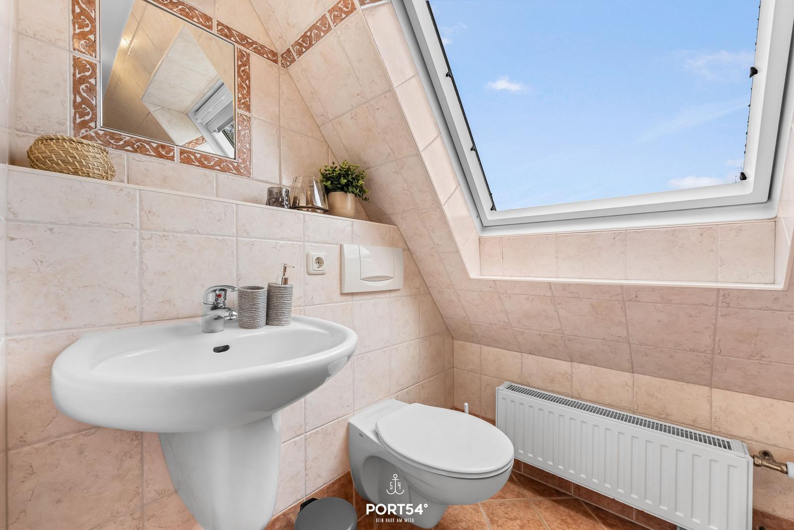 Badezimmer mit Waschbecken, Toilette und Dachfenster.