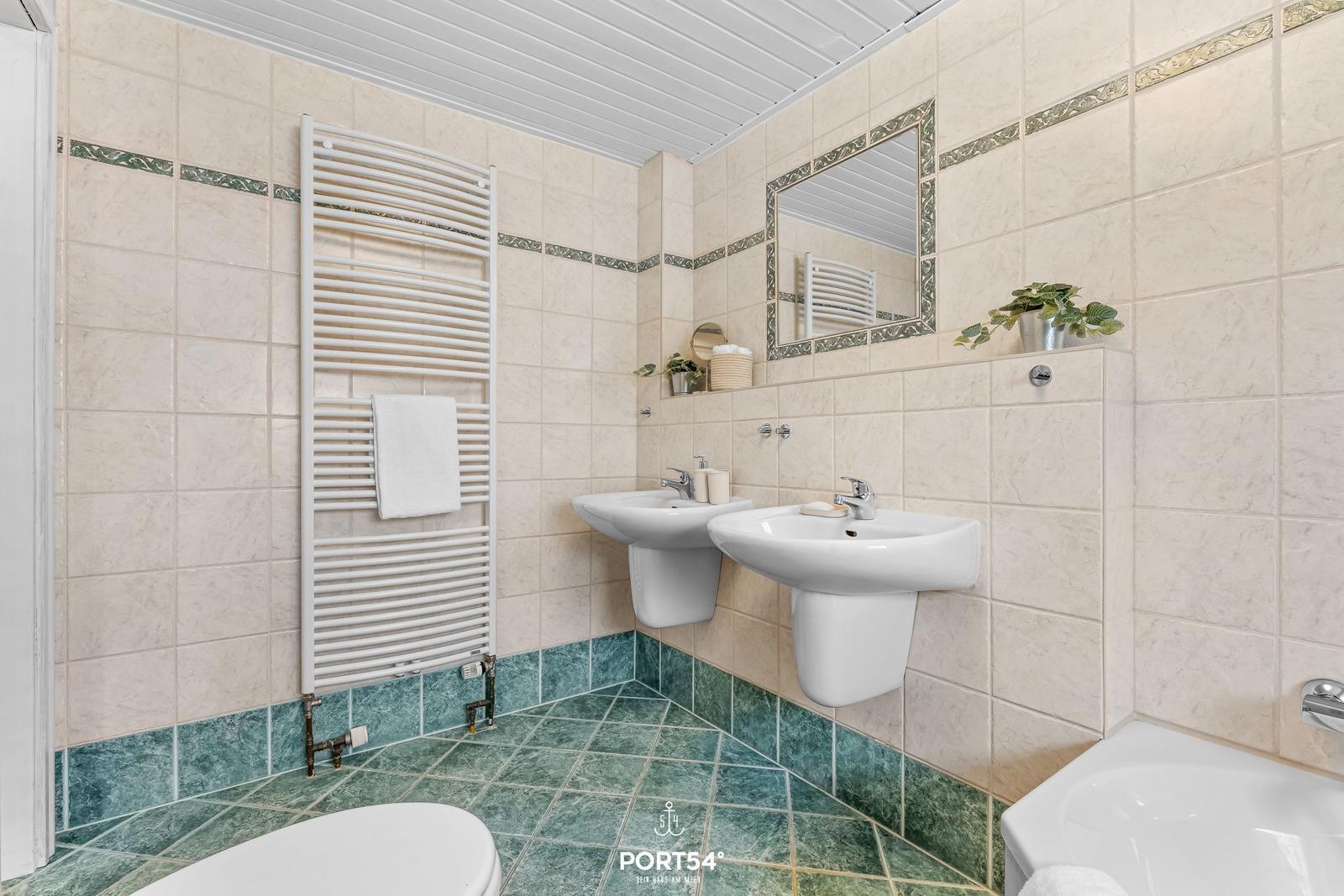 Badezimmer mit zwei Waschbecken, Dusche und Heizkörper