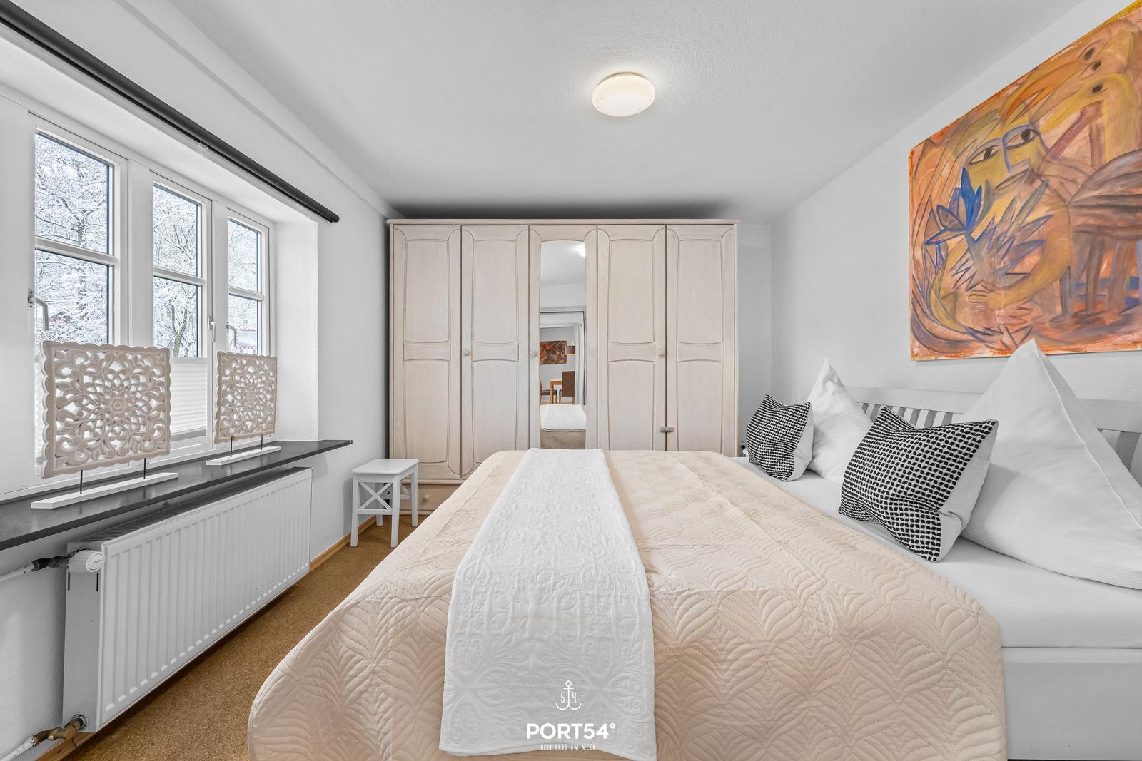 Schlafzimmer mit Bett, Kleiderschrank und Fenster mit Blick auf Schnee.