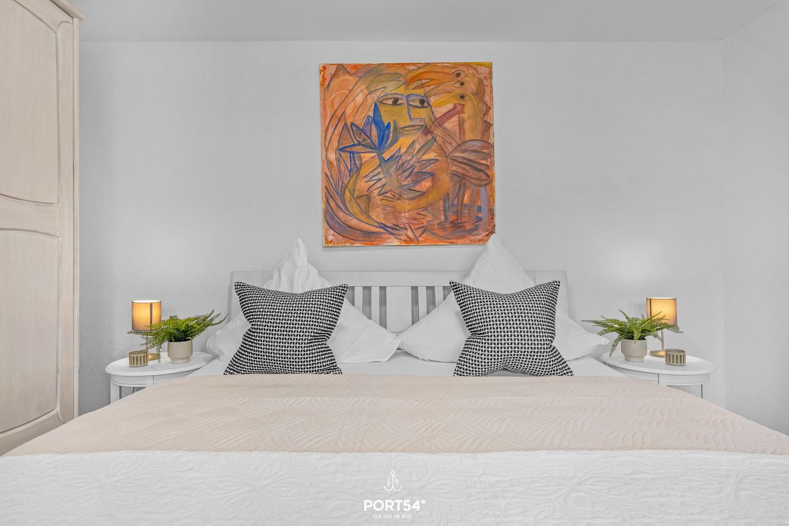 Schlafzimmer mit Bett, Nachttischen und Wandbild.