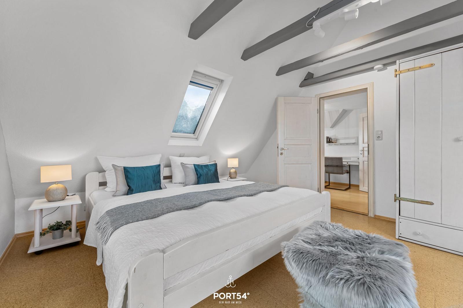 Schlafzimmer mit Dachschrägen, Dachfenster, Bett, Nachttische und Kleiderschrank.