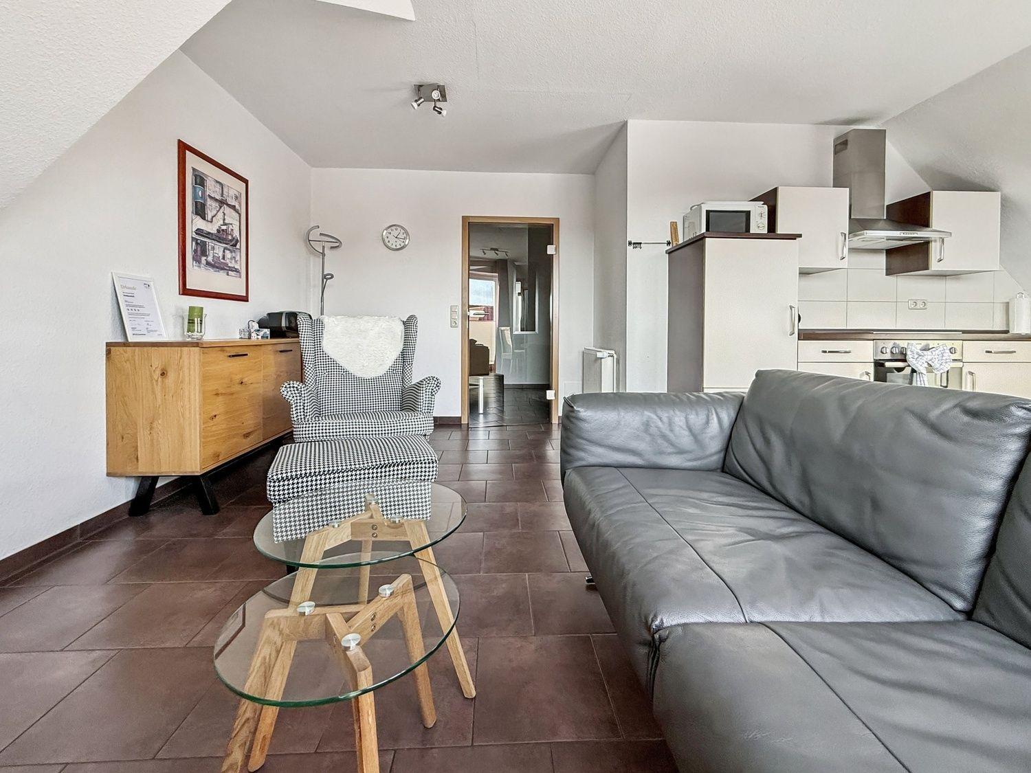 Wohnbereich mit Sofa, Sessel und Küchenzeile