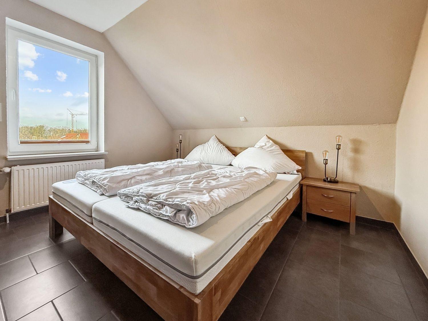 Schlafzimmer mit Doppelbett, Nachttisch und Fenster mit Blick.