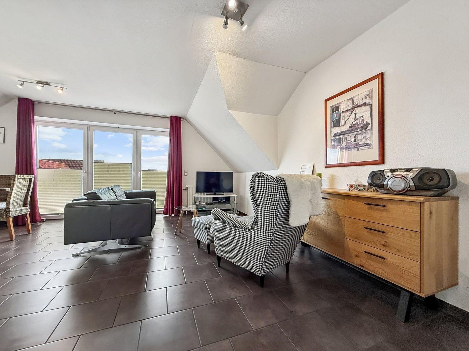 Wohnzimmer mit Sofa, Sessel und TV. Fenster mit Blick. Holzmöbel und Wandbild.