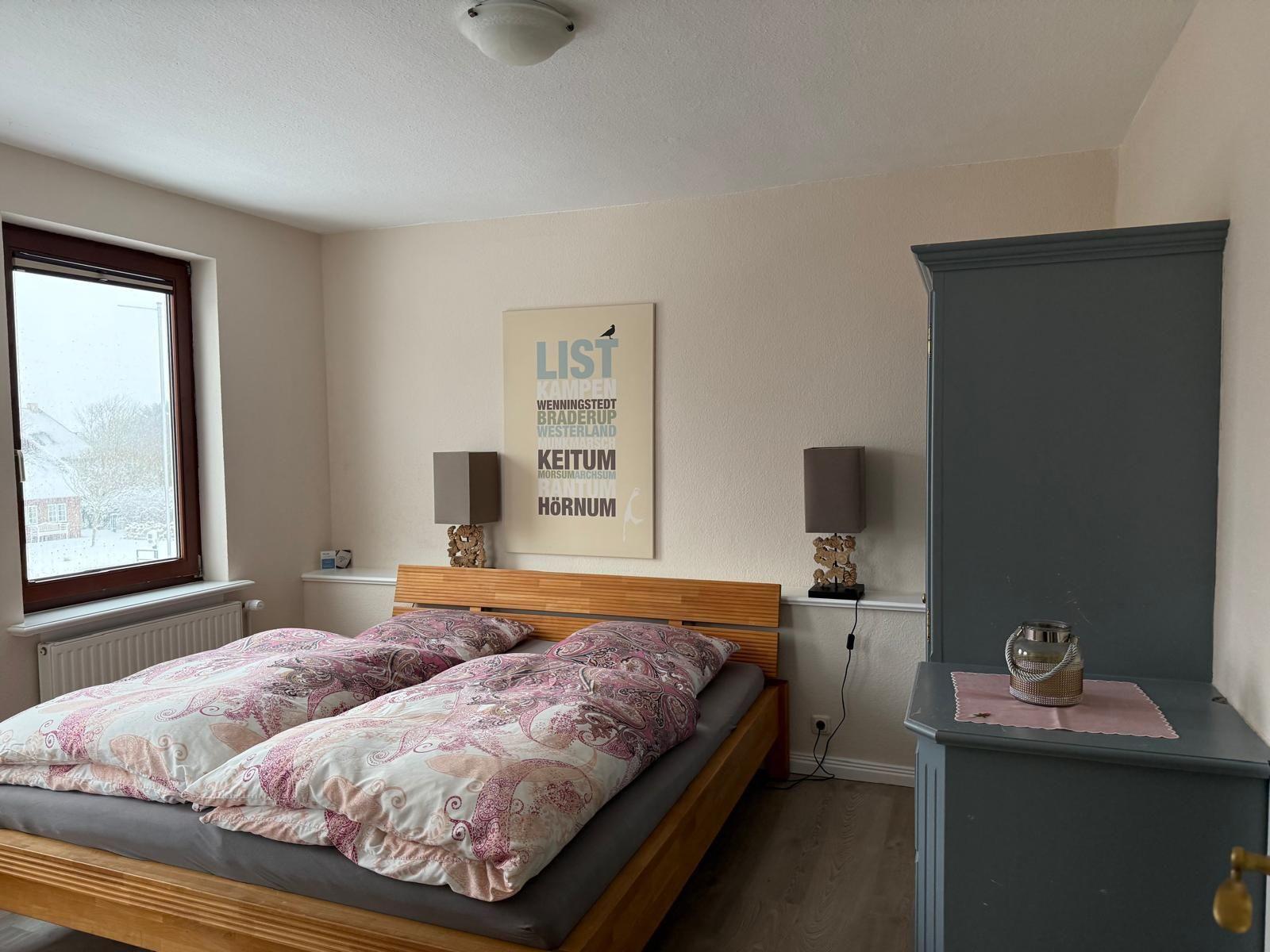 Schlafzimmer mit Doppelbett, Fenster und Kleiderschrank.