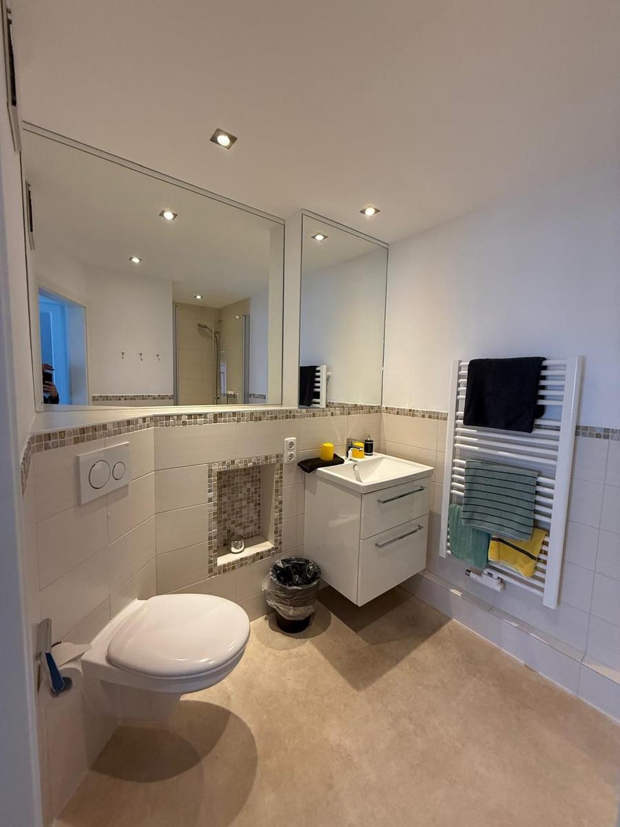 Badezimmer mit Toilette, Waschbecken und Heizkörper mit Handtüchern.