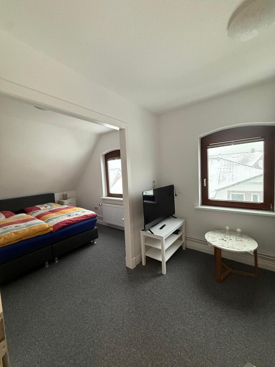 Zimmer mit Bett, TV und Fenster. Blick auf Dachgeschoss.