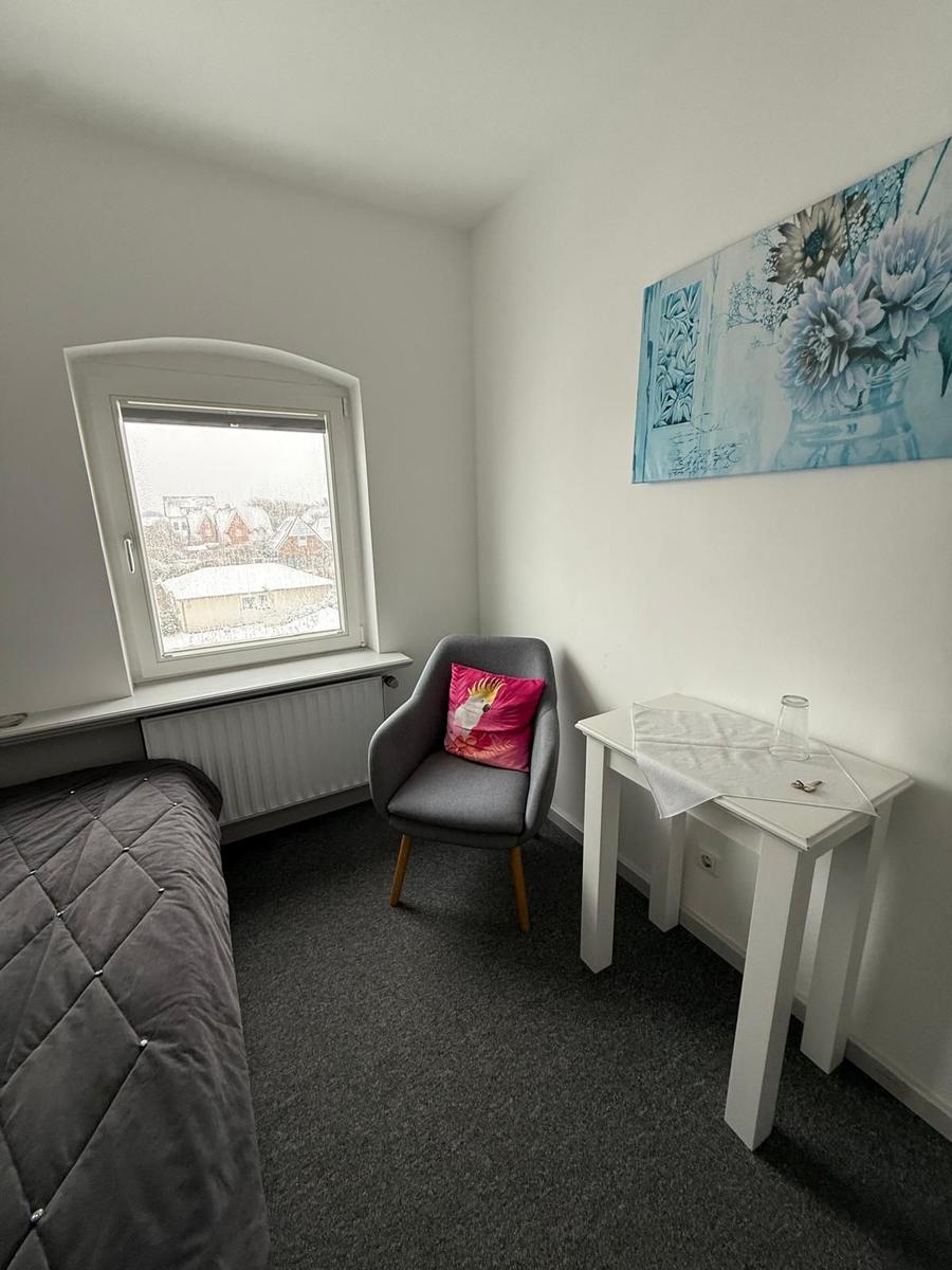 Zimmer mit Bett, Stuhl, Tisch und Fenster mit Blick auf Schnee.