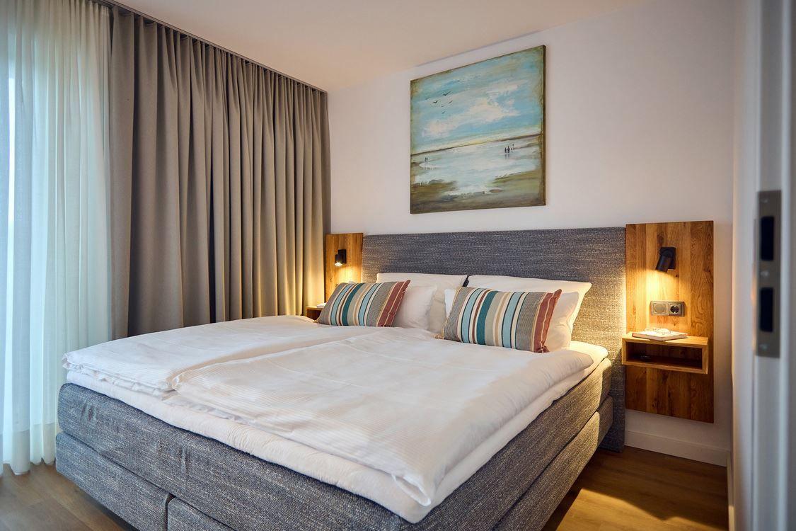 Schlafzimmer mit Doppelbett, Wandbild und Holznachttischen