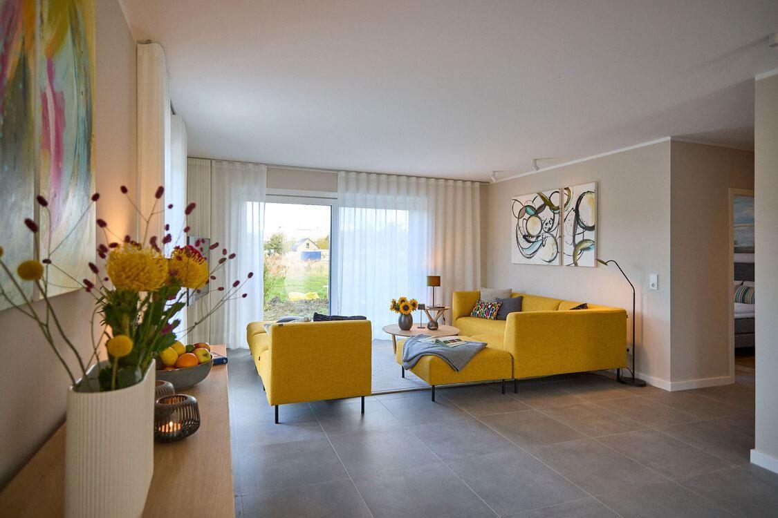 Wohnzimmer mit gelben Sitzgelegenheiten, großen Fenstern und moderner Einrichtung.