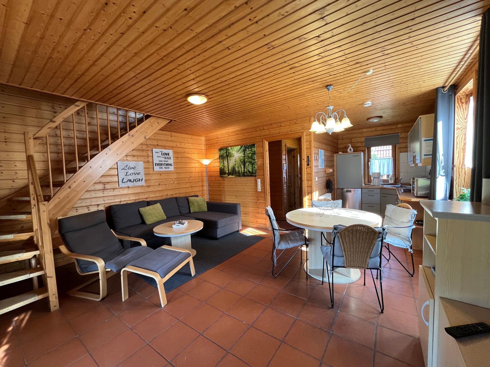 Wohnbereich mit Sofa, Essbereich und Küchenzeile in Holzhaus.