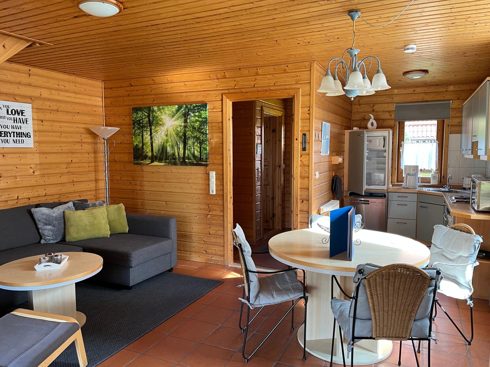 Wohnbereich mit Sofa, Esstisch und Küche in Holzhaus