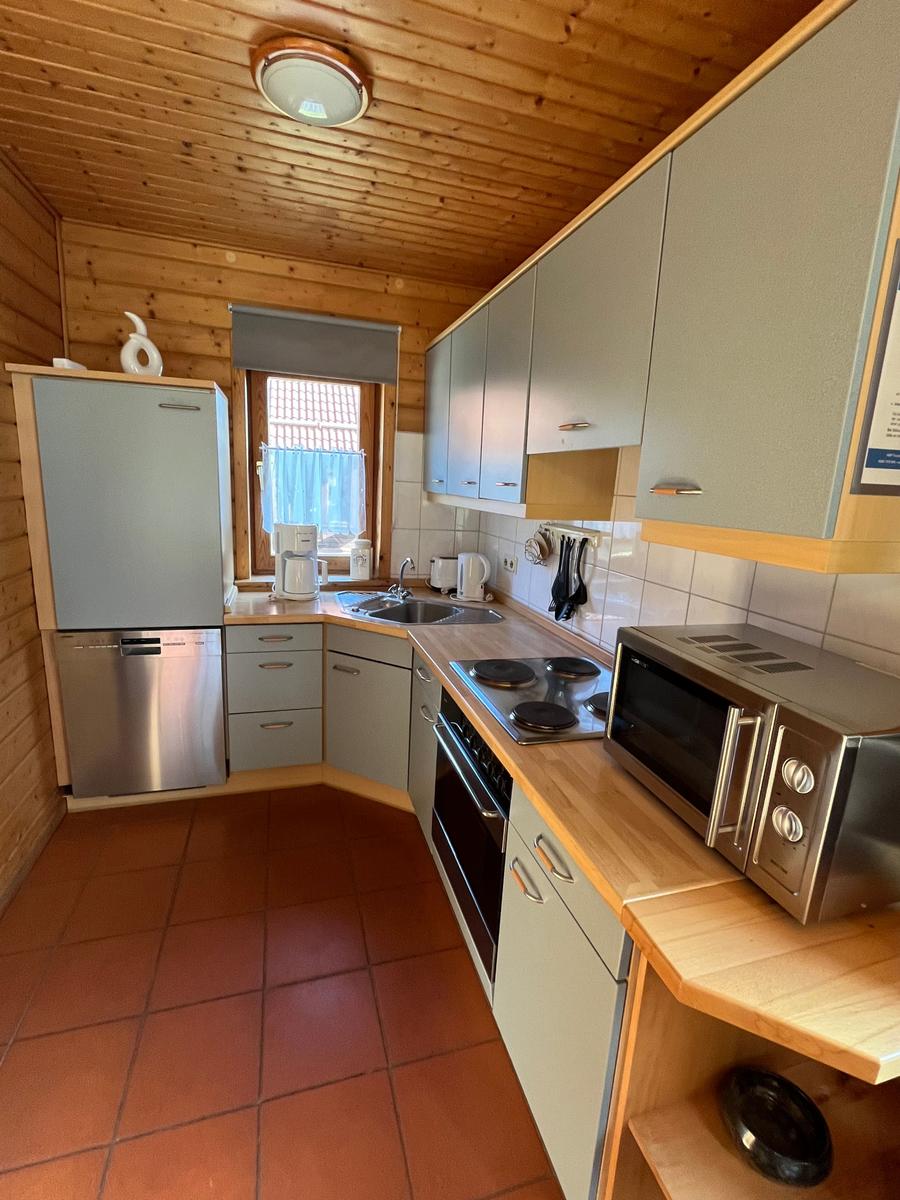 Küche mit Holzdecke, grauen Schränken und Edelstahlgeräten.