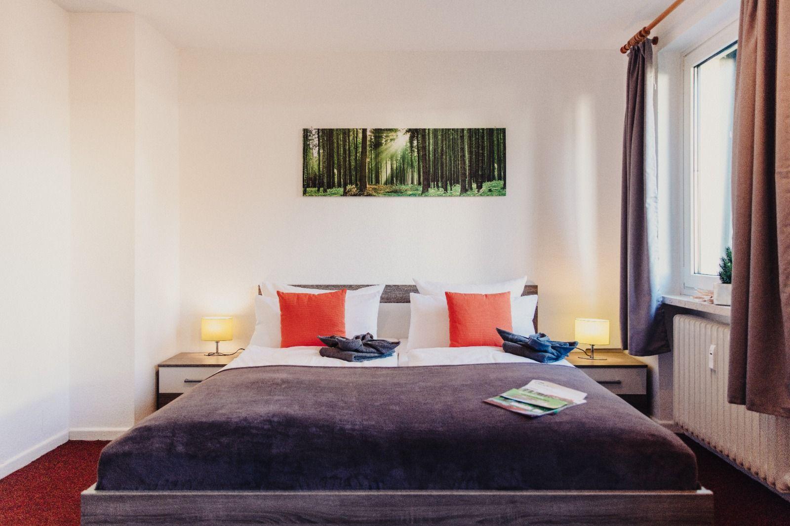 Schlafzimmer mit Doppelbett, zwei Nachttischen und Wandbild