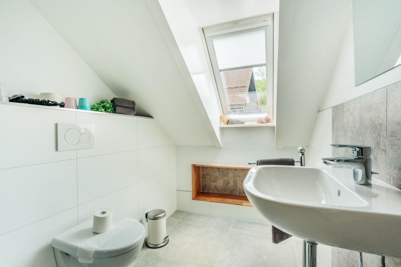 Badezimmer mit Dachfenster, Waschbecken und Toilette.