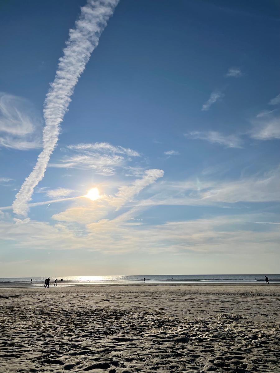 Strand mit Sonne und Wolken am Horizont